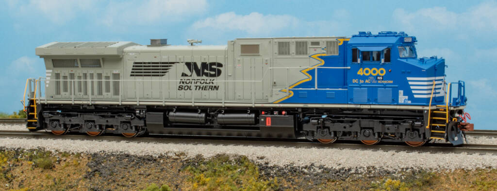 Color photo of HO scale diesel painted blue, yellow, gray, and black on scenicked base with a sky blue backdrop.