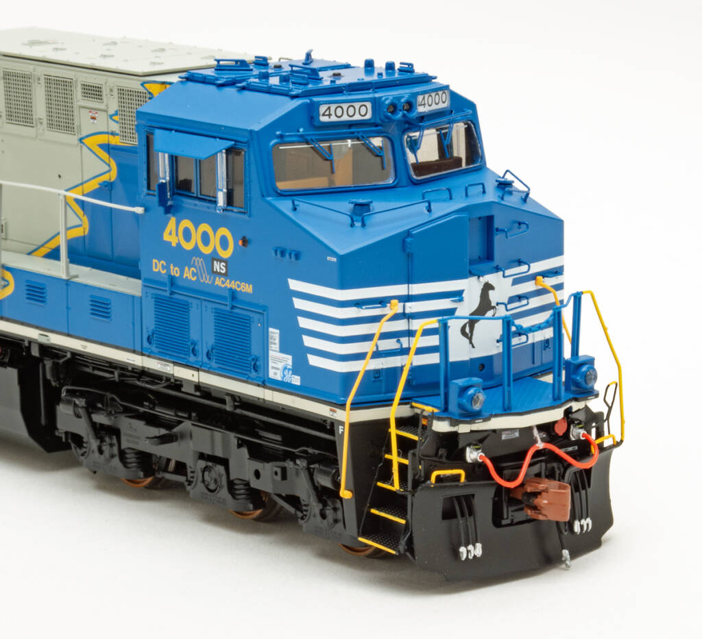 Color photo showing nose of HO scale diesel locomotive painted blue, gray, yellow, black, and white on white background.