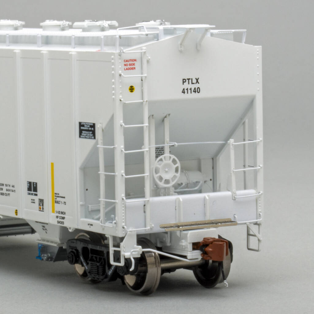 Color photo showing B end of HO scale four-bay covered hopper painted light gray with black, white, and yellow graphics on medium gray background