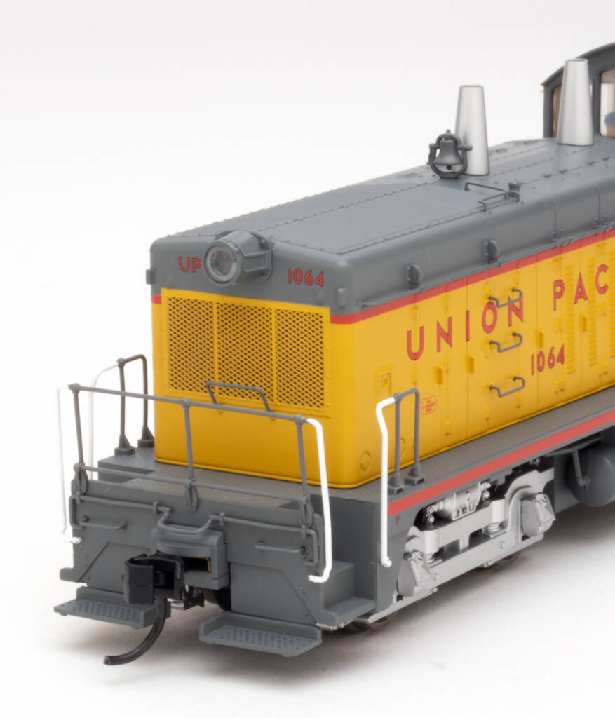 Color photo showing front of hood on HO scale switcher painted yellow and gray with red graphics on white background.