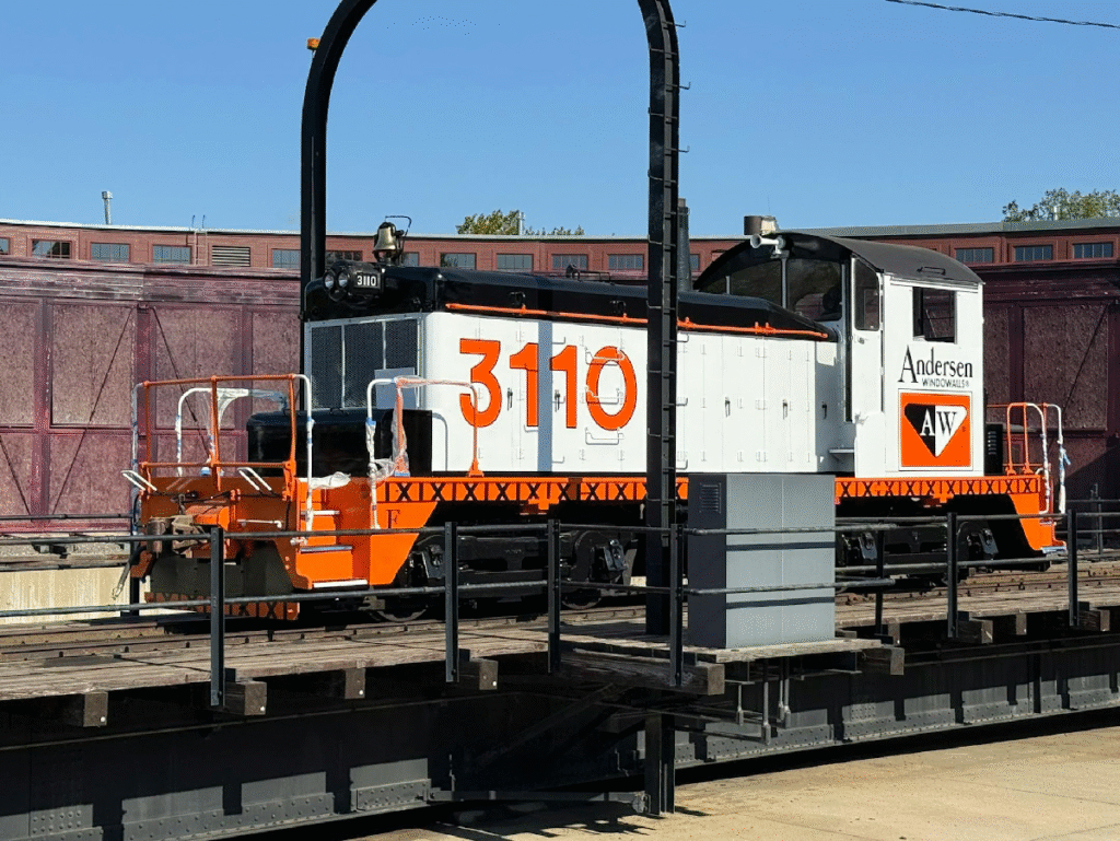Black, white, and orange diesel locomotive on a turntable.