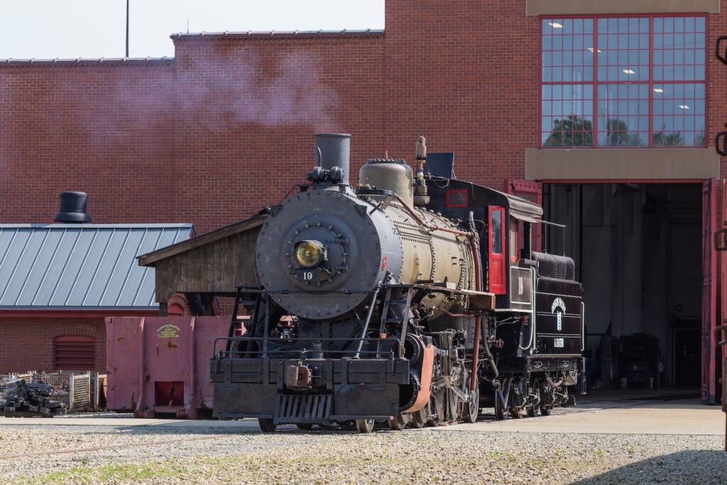 Steam locomotive undergoing work under steam outside of roundhouse