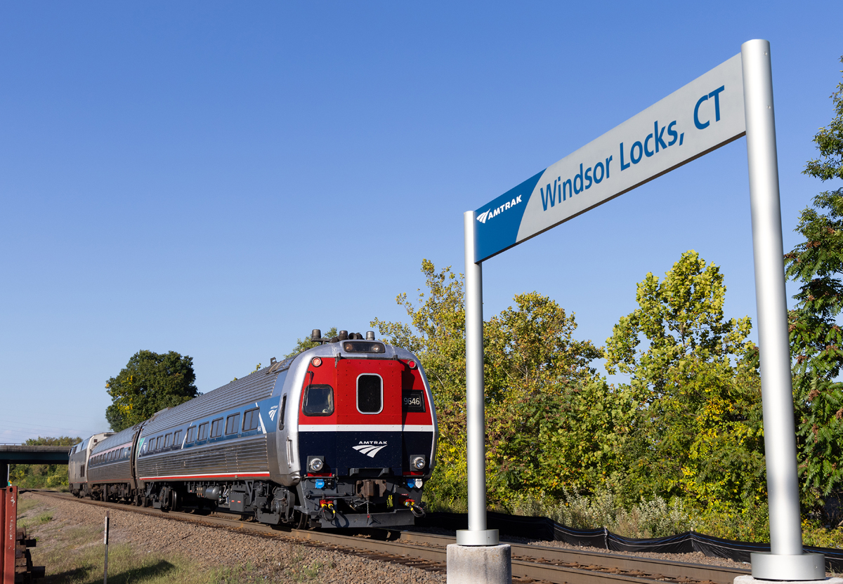 Cab car with blue and red front passing Amtrak "Windsor Locks station sign
