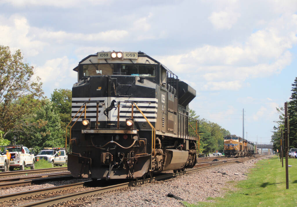 Black locomotive with train with yellow locomotives in background