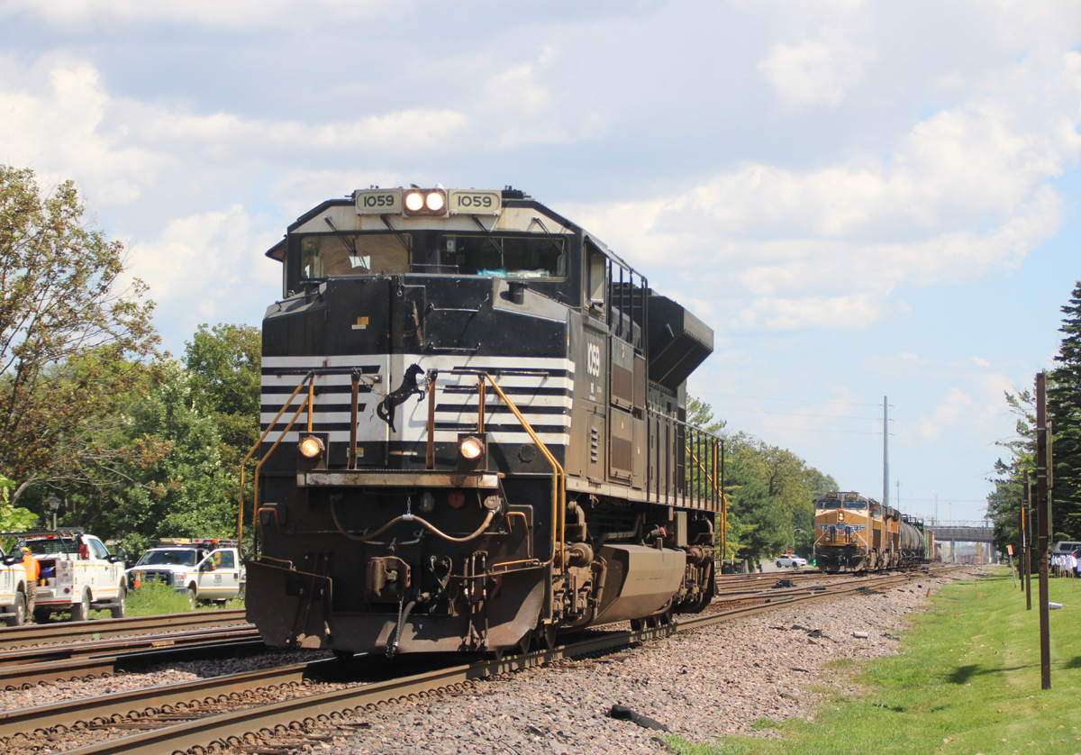 Black locomotive with train with yellow locomotives in background