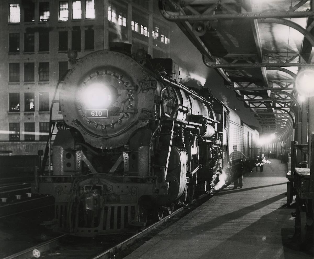 Steam-powered passenger train waiting at a station at night