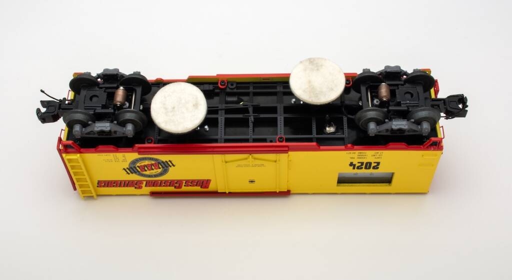 underside of model boxcar with two cleaning pads