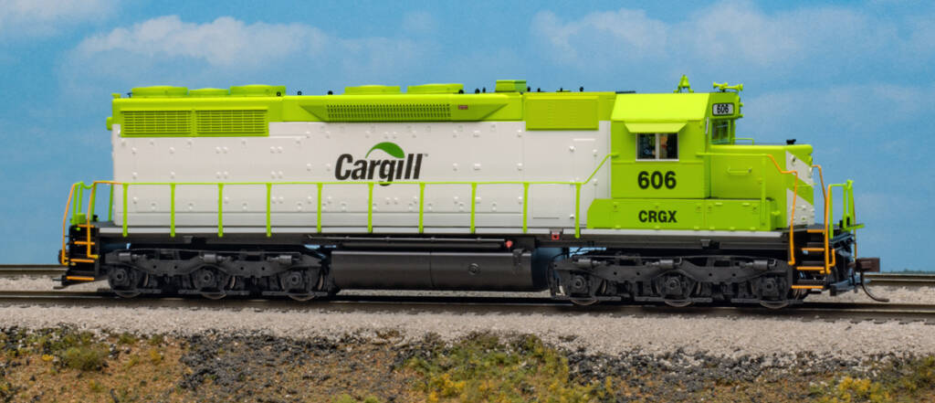 Color photo of HO scale six-axle hood unit painted bright green and white with black graphics on scenicked base with a sky backdrop.