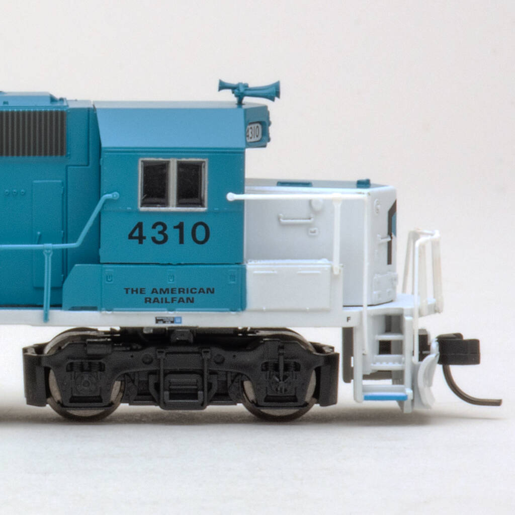 Color photo of showing engineer's side of cab and short hood on an N scale EMD GP38-2 painted blue and white with black graphics on white background.