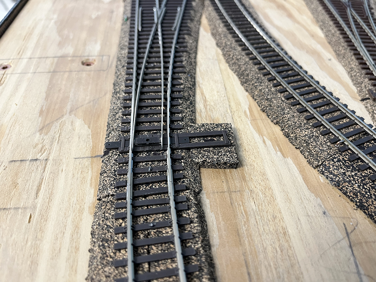 Model railroad track on cork roadbed on a wooden surface