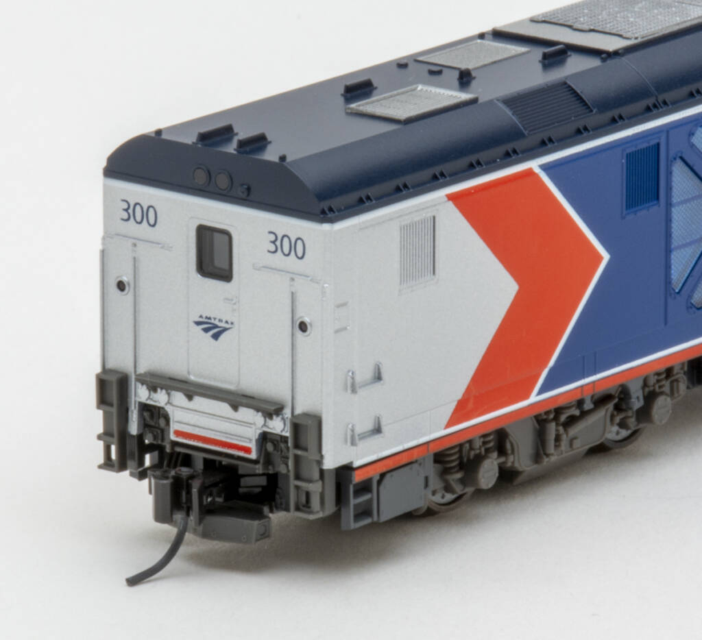 Color photo showing rear of modern passenger diesel painted red, white, gray, and blue with white graphics on white background.
