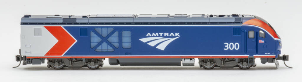 Color photo showing engineer’s side of modern passenger diesel painted red, white, gray, and blue with white graphics on white background.