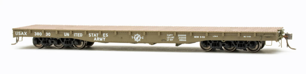 Color photo of HO scale flatcar painted United States Army Green with white graphics, painted wood deck, and black six-axle trucks with metal wheels on white background.