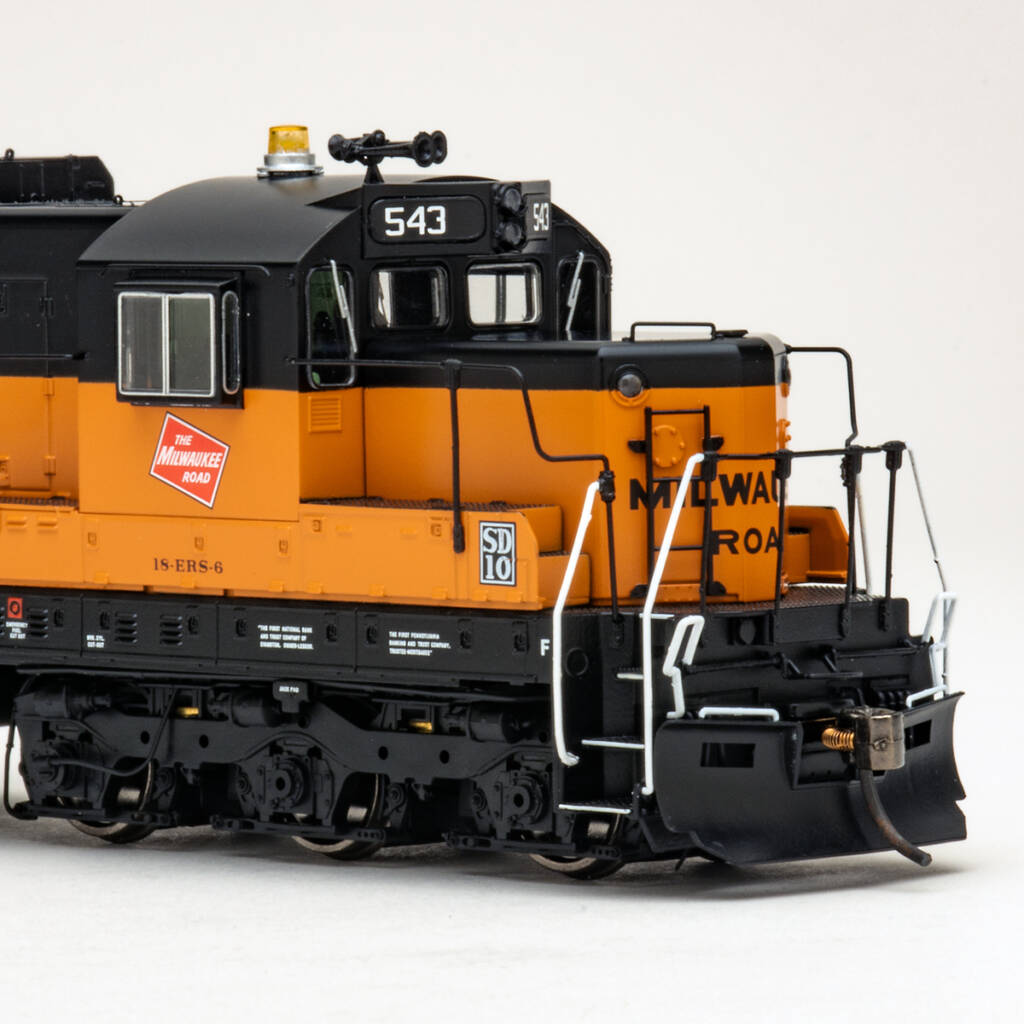 Color photo showing nose of HO scale SD10 diesel locomotive painted orange and black on white background.