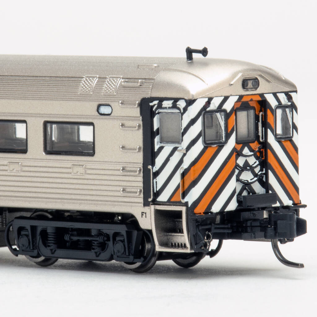 Color photo showing end of N scale Budd Rail Diesel Car with stainless steel finish and black, orange, and white stripes on white background