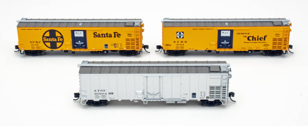 Color photo showing three N scale steel refrigerator cars, two painted yellow with blue door and brown roof and one painted silver, all on white background.