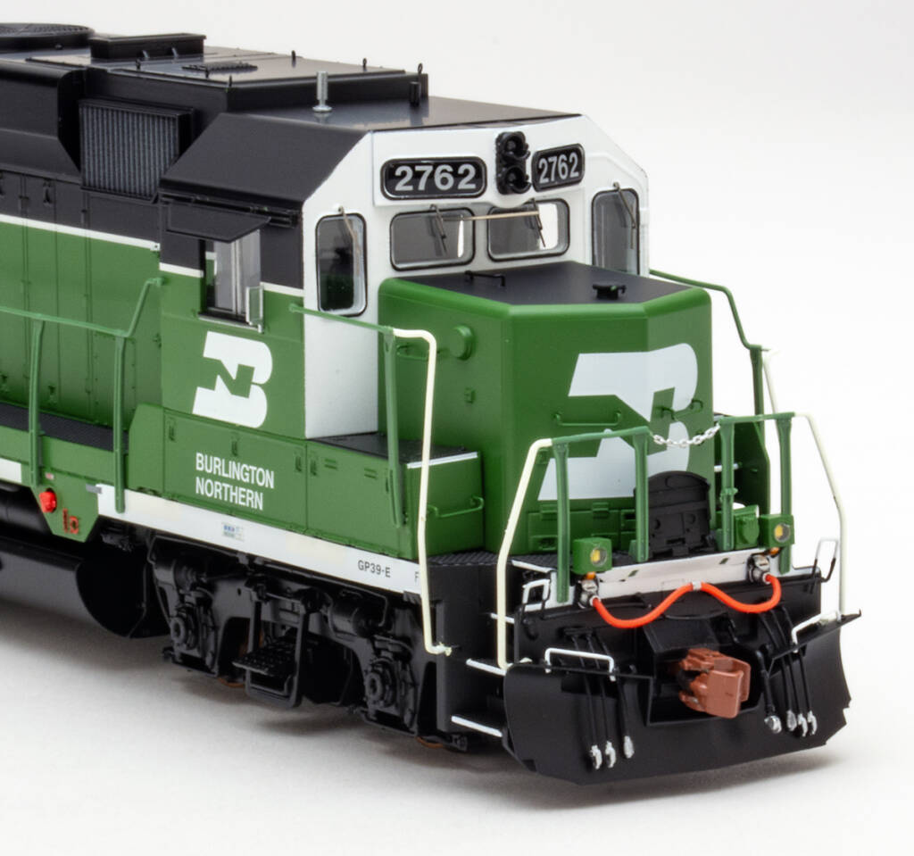 Color photo showing cab and short hood of HO scale diesel painted green, white, and black on white background.