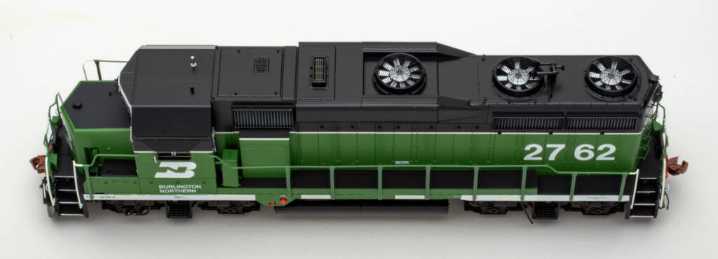Color overhead photo of HO scale diesel locomotive painted green, white, and black on white background.