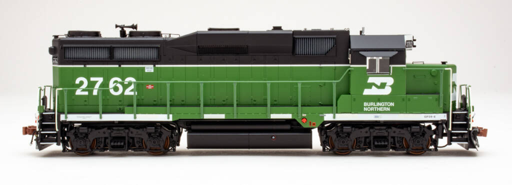 Color photo showing engineer’s side view of HO scale hood diesel painted green, black, and white on white background.