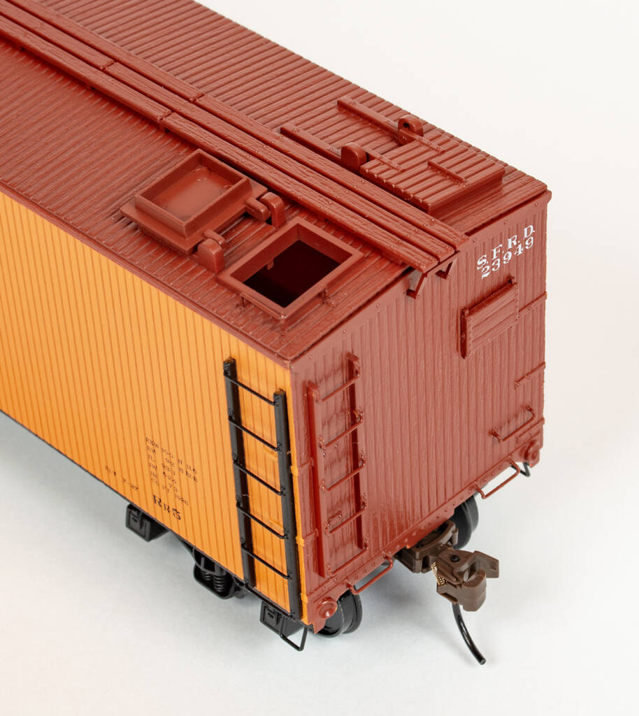Color photo showing side, end, and roof of S scale wood refrigerator car painted yellow-orange and mineral red.