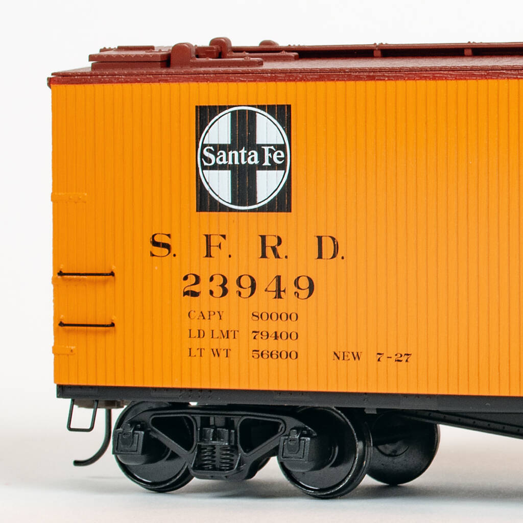 Color photo showing portion of an S scale refrigerator car painted yellow-orange, mineral red, and black with black and white graphics.