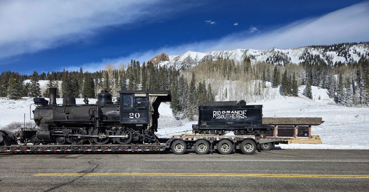 Steam locomotive on a flatbed trailer in a mountain pass. Rio Grande Southern No. 20 visits Durango.