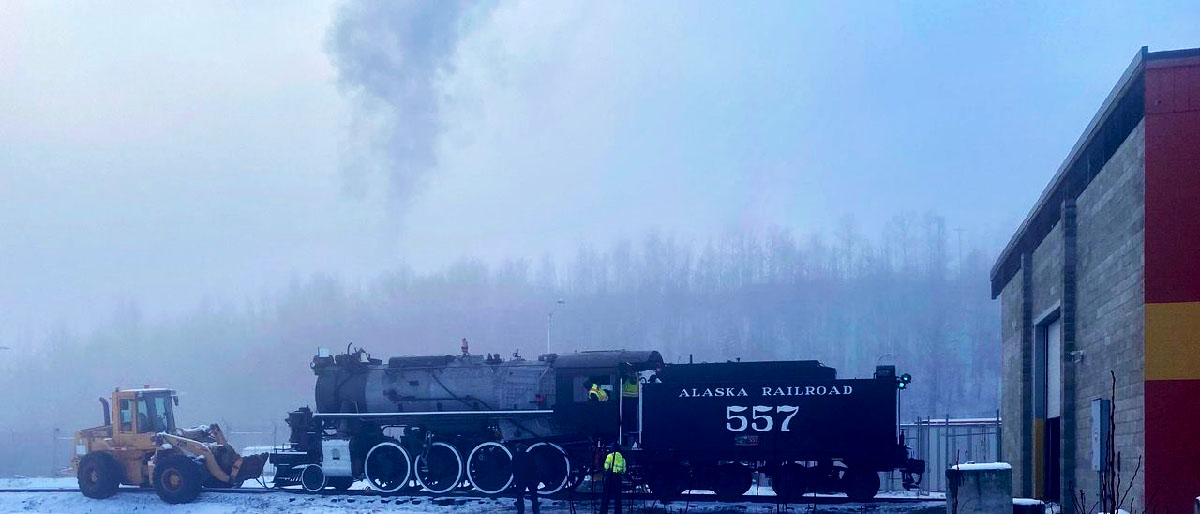 Steam locomotive outside shop on a foggy day for a test firing. Alaska No. 557 fired up after 60 years.