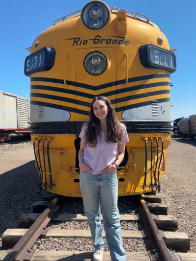 Young individual standing in front of a static-displayed diesel locomotive