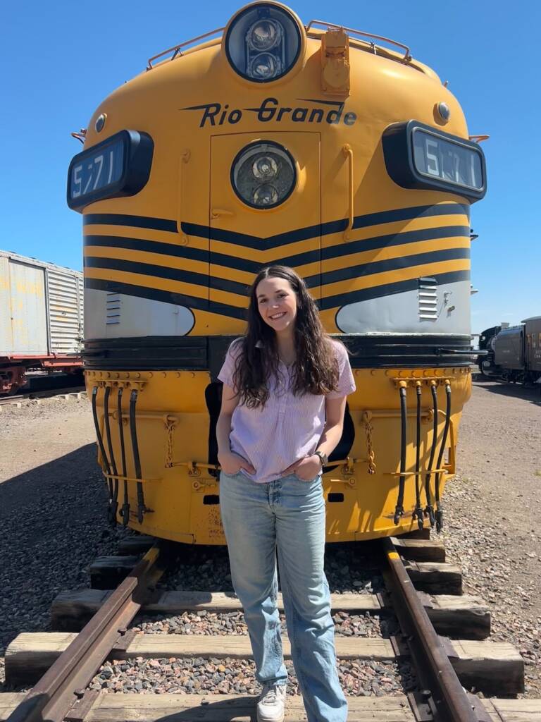 Young individual standing in front of a static-displayed diesel locomotive