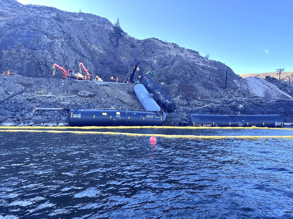 View from water of derailed cars and booms to contain spilled fuel