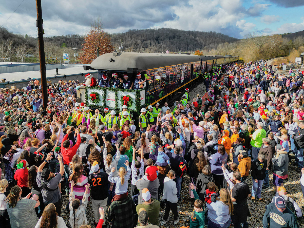 Large crowd surrounding rear of passenger train with open-platform observation car