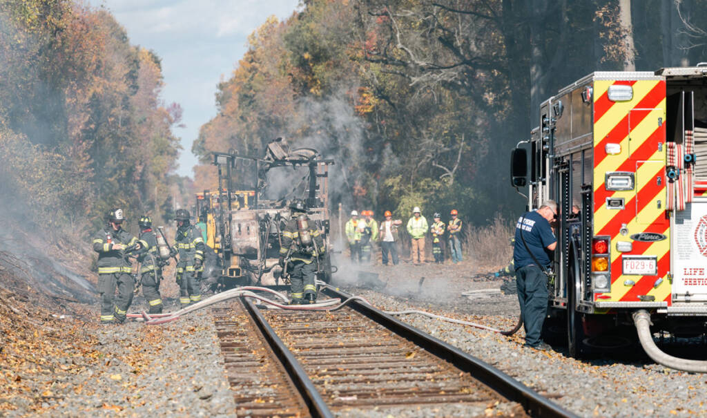 Firemen work near smoking remains of maintenance-of-way machinery destroyed by explosion
