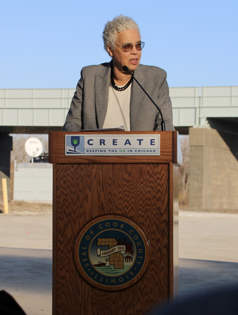Woman speaking at podium with CREATE sign and Cook County, Ill., logo