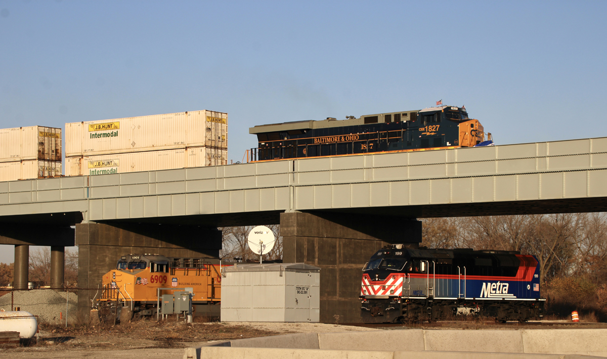 CSX Intermodal train led by single locomotive passes over Union Pacific and Metra locomotives on bridge