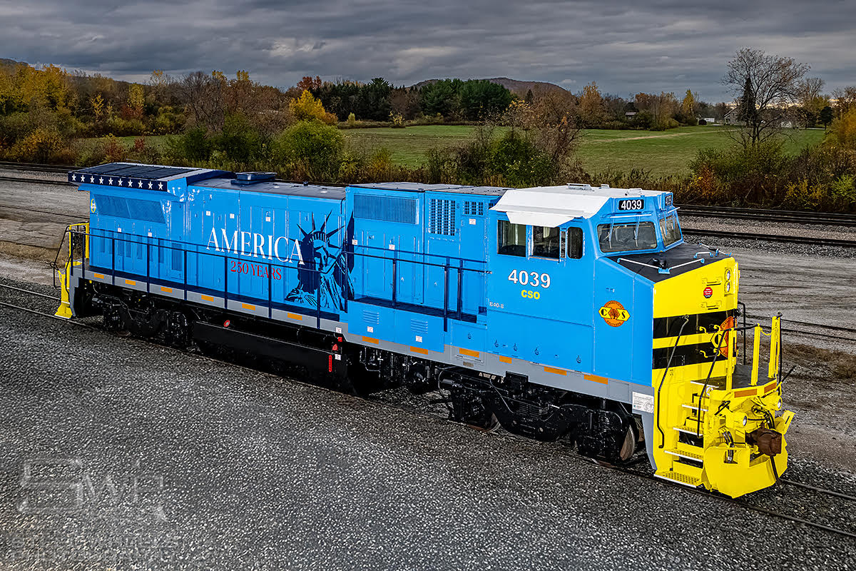 Light blue and yellow locomotive with America 250th lettering