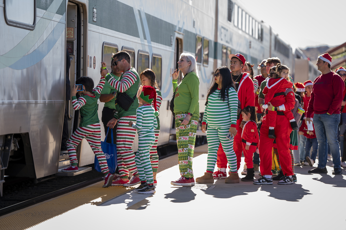 People in pajamas or holiday clothing waiting to board train
