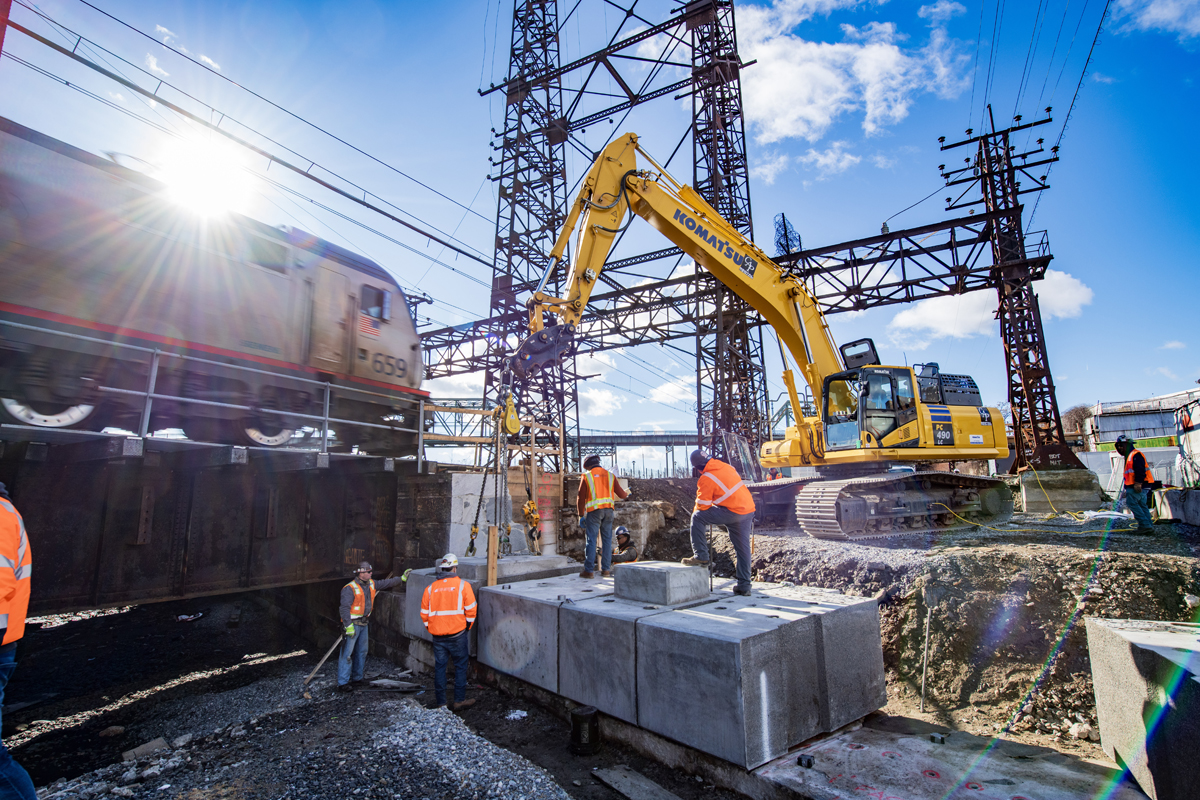 Electric passenger locomotive passes construction workers and machinery