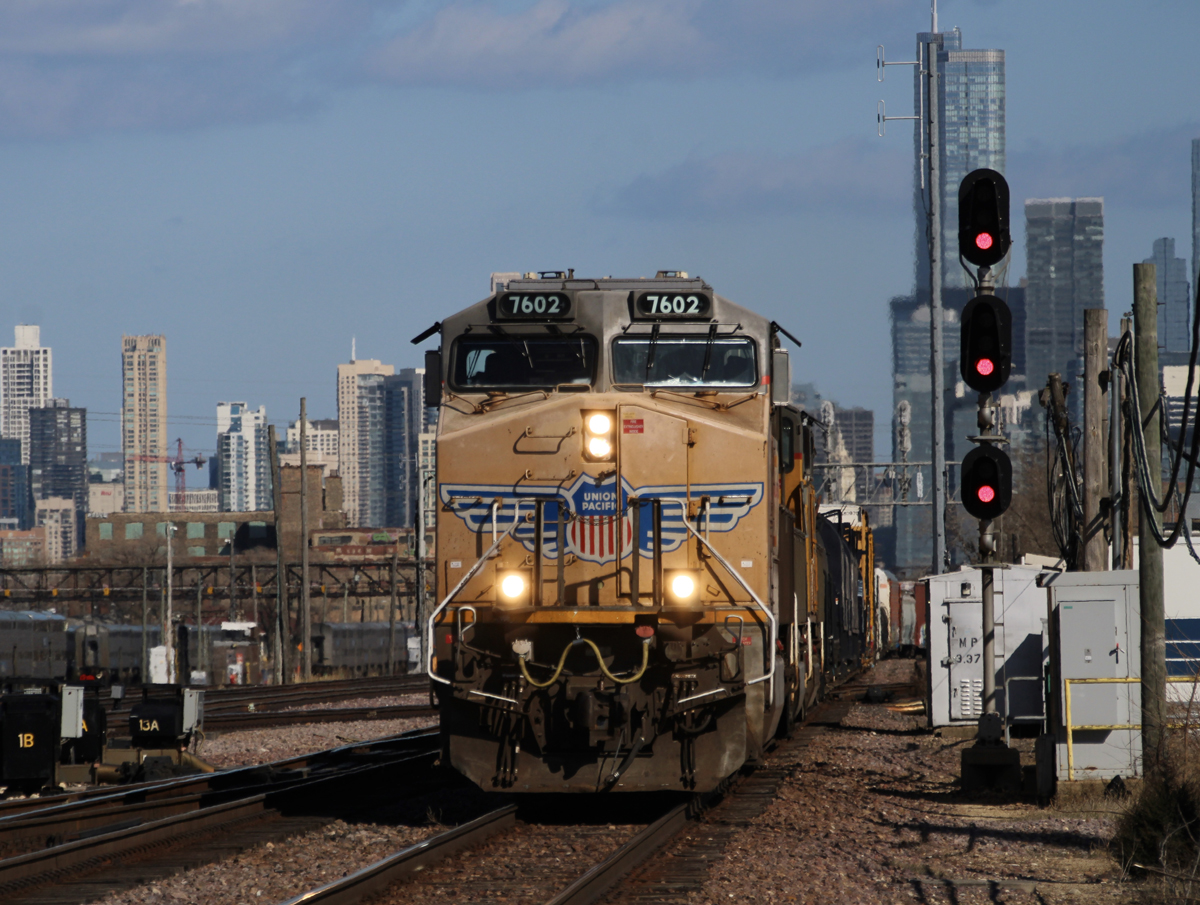 Freight train led yellow locomotive with Chicago skyline in background