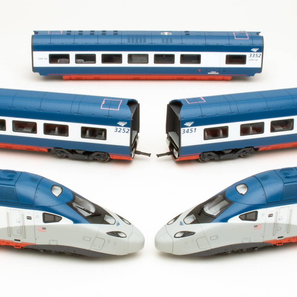 Color photo showing two modern streamlined locomotives and three passenger cars in red, white, and blue paint on white background.