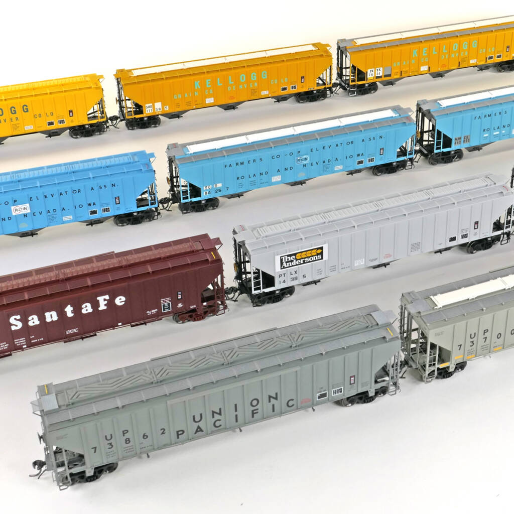 Color photo showing group of HO scale three-bay covered hoppers with exterior posts in various paint schemes on white background.