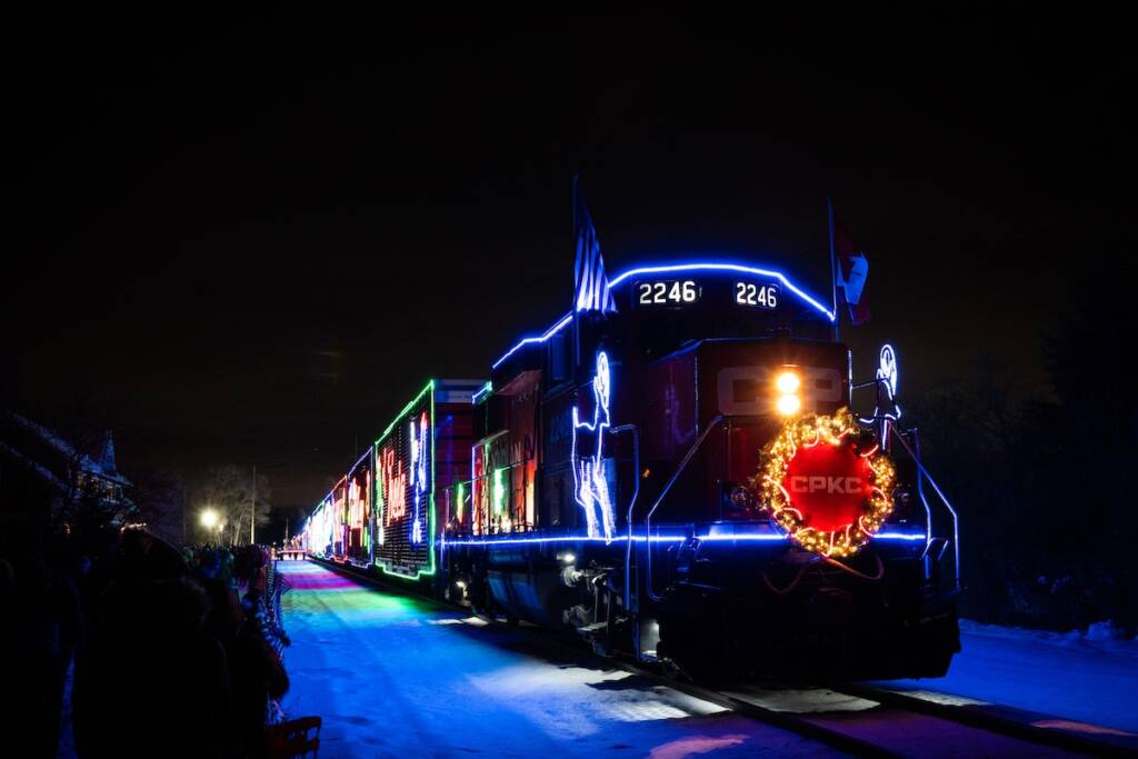Diesel-powered trains with holiday lights stopped at a station