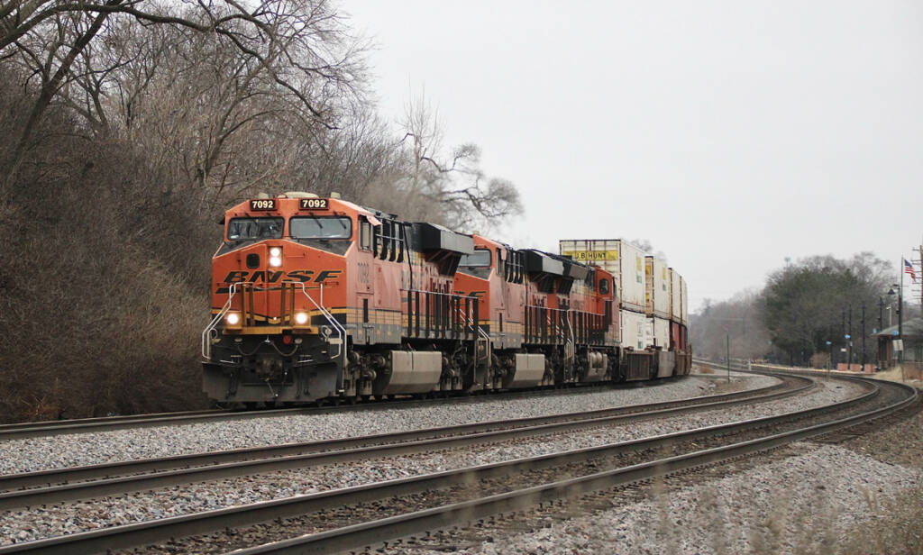 Intermodal train woth orange locomtives rounding curve.