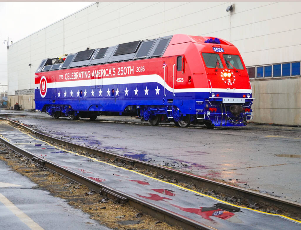 Red, white, and blue locomotive outside shop building