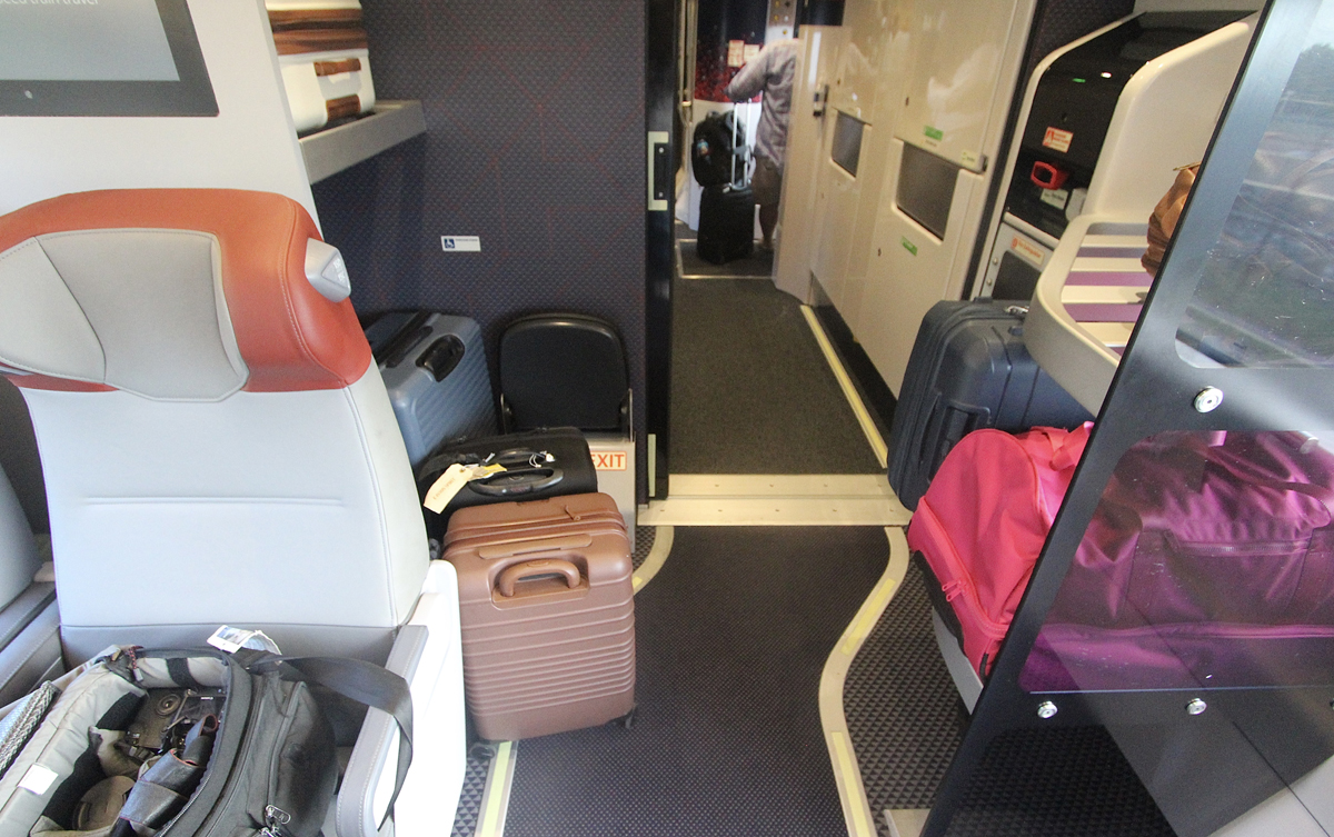 Baggage on floor next to luggage storage rack in Acela coach