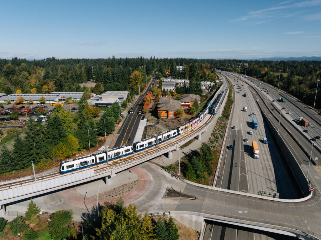 Aerial view of light rail trains on tracks next to freeway