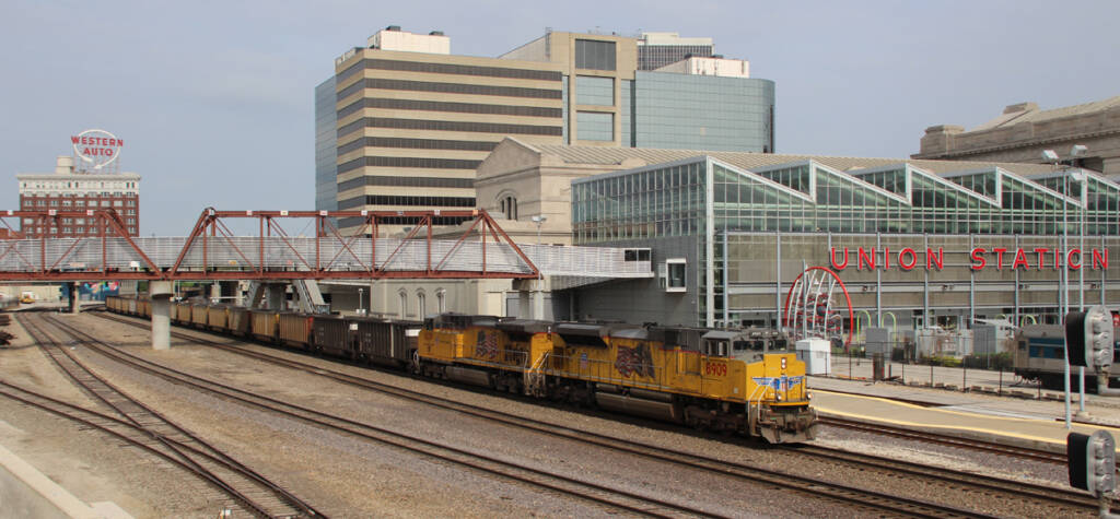 Freight train with yellow locomotives passing building with "Union Station" sign