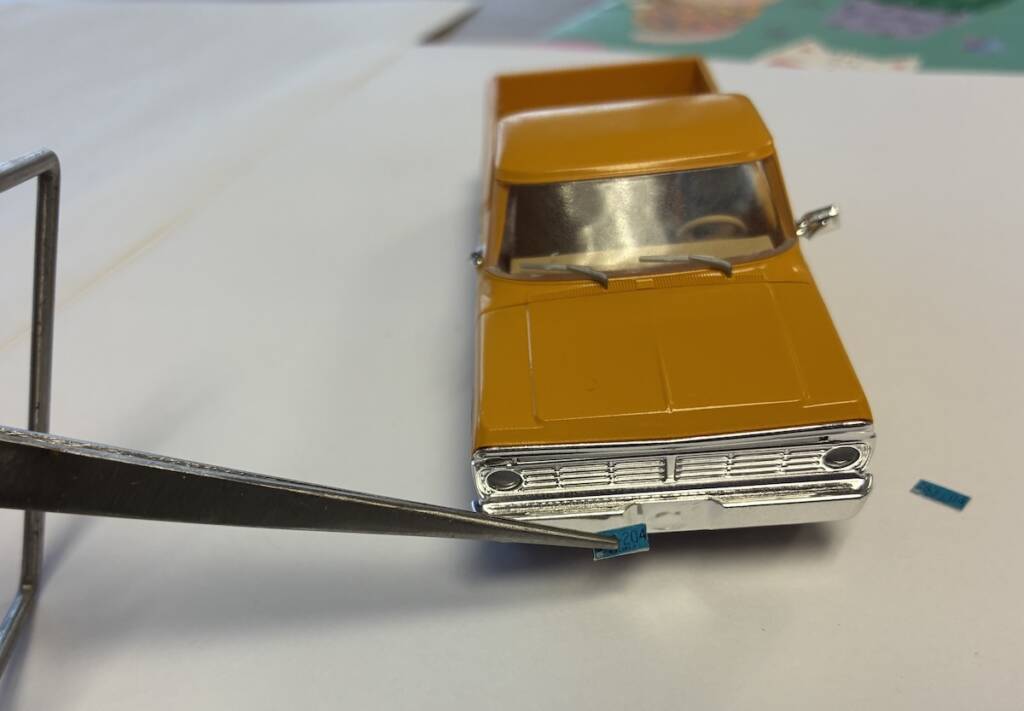 tweezers applying license plate to model truck