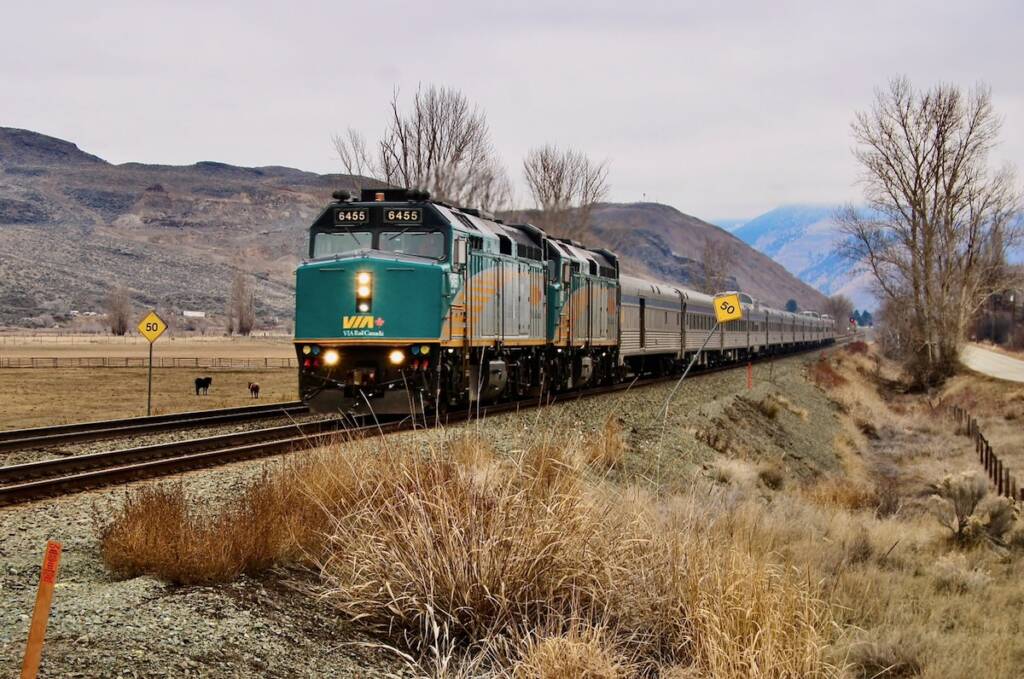 Passenger train on straight track with mountain backdrop