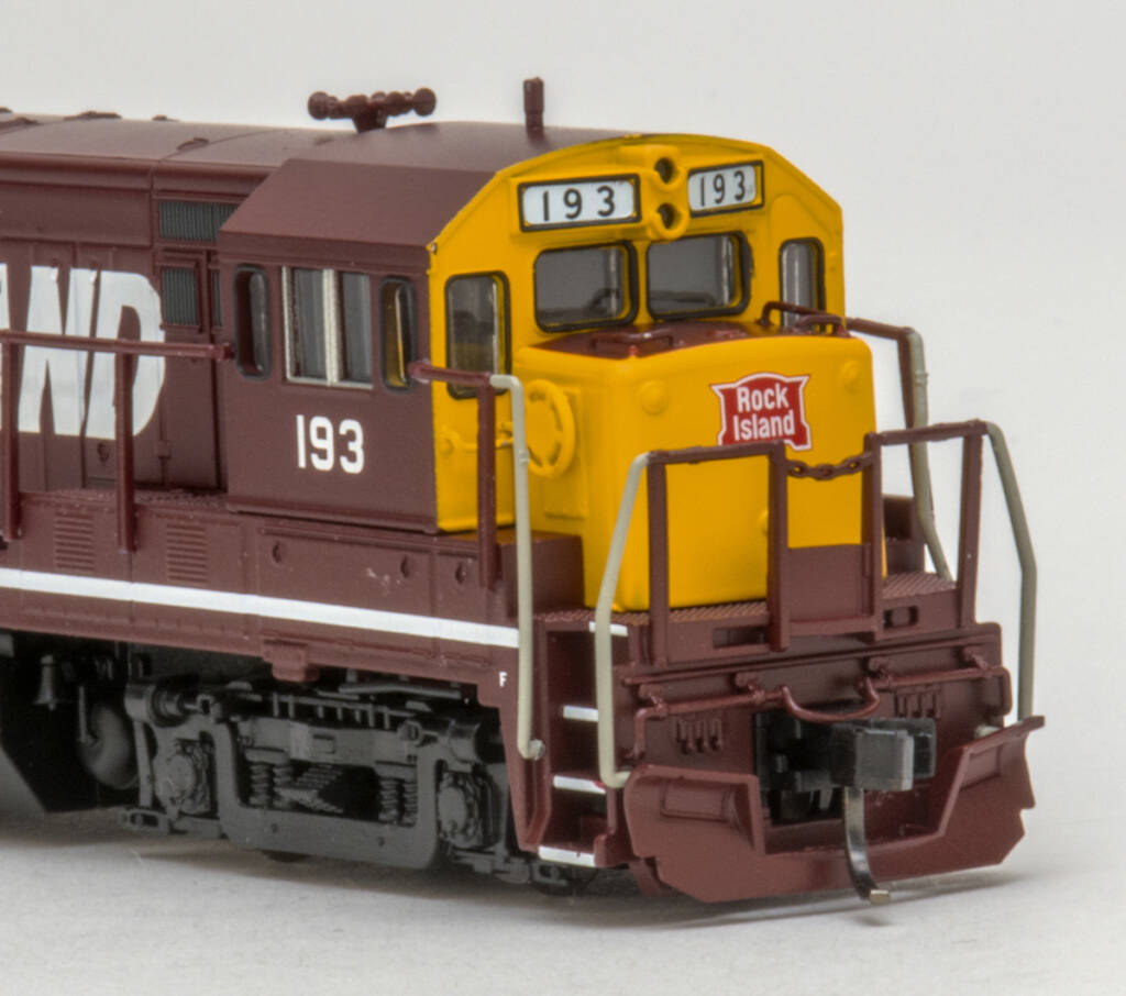 Color photo showing nose of N scale diesel painted maroon, yellow, and black with red and white graphics on white background