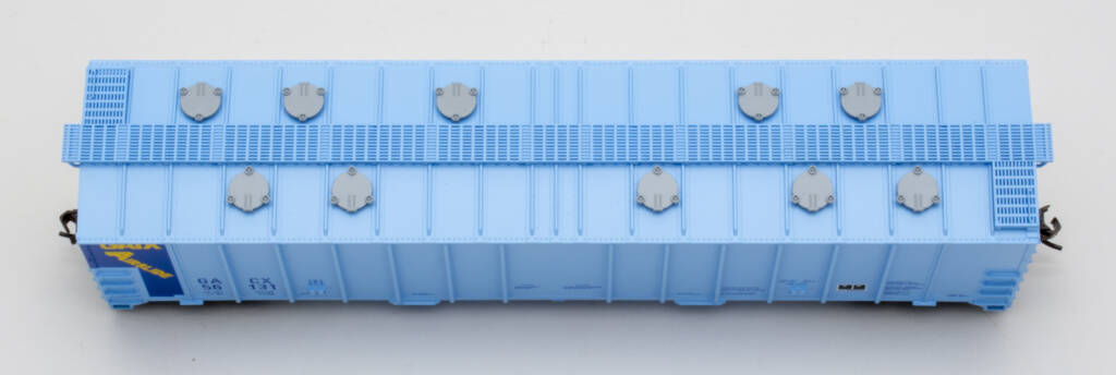 Color photo showing roof of HO scale covered hopper painted two-tone blue with blue, yellow, black, and white graphics and gray hatch covers on white background.